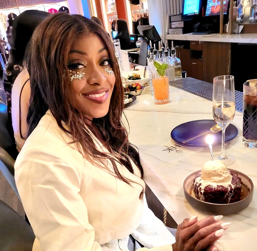 Shamekka sitting at bar with celebratory cake in front of her